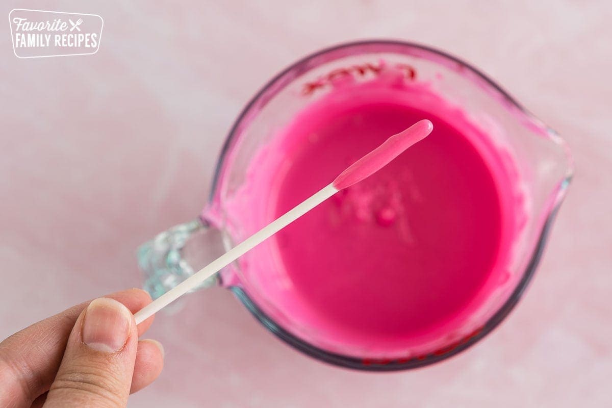 A cake pop stick dipped in pink melted chocolate