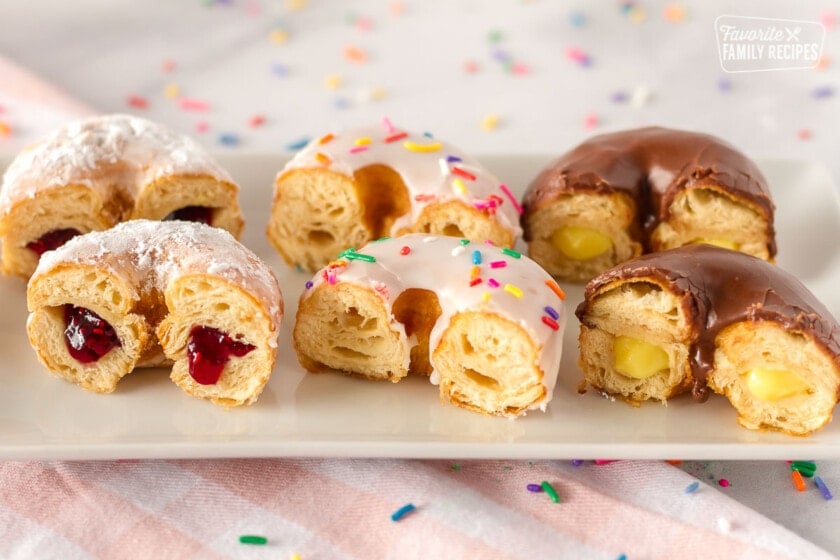 Close up of cronuts cut in half showing raspberry, plain, and vanilla filling
