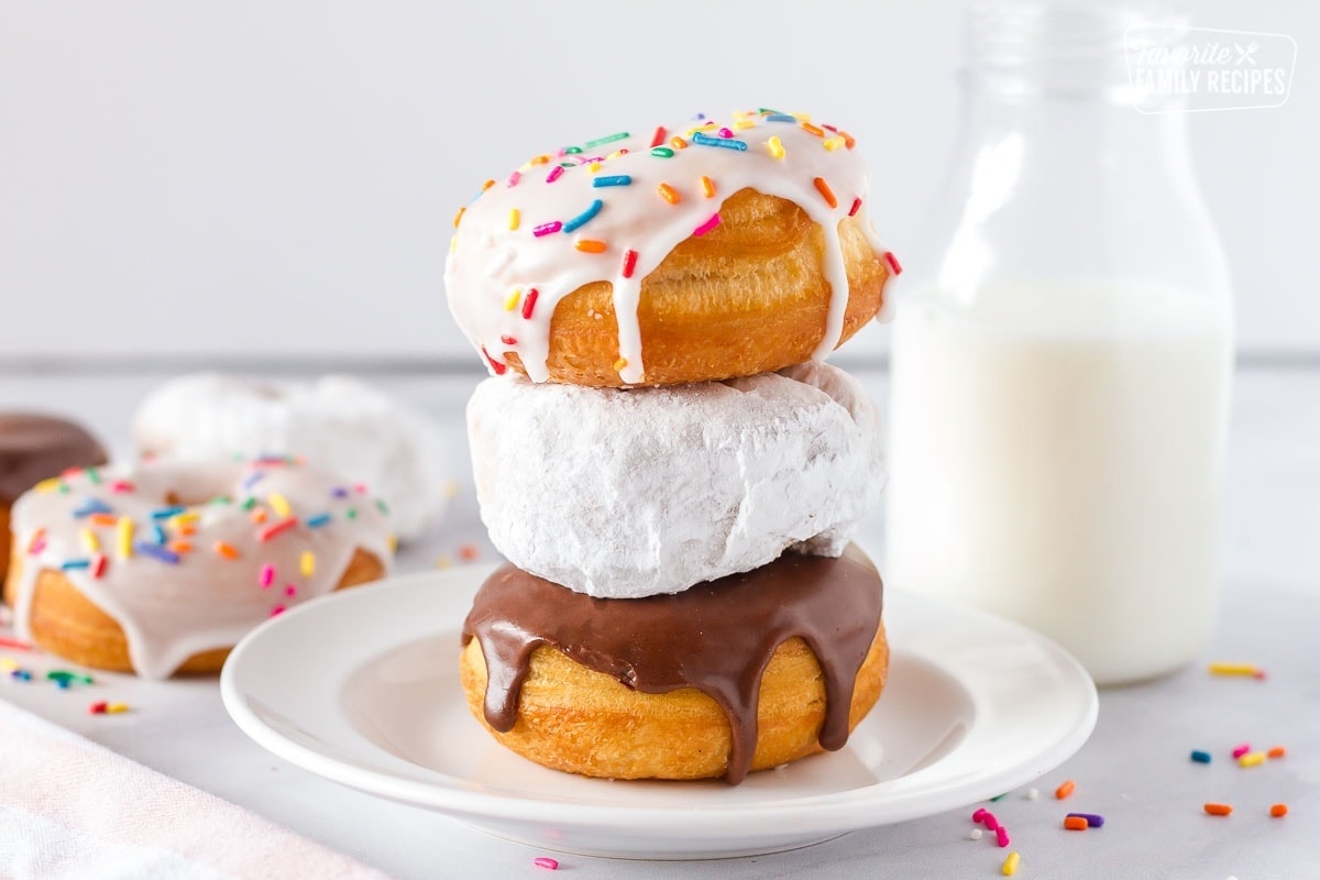 Stack of three decorated cronuts on a white plate