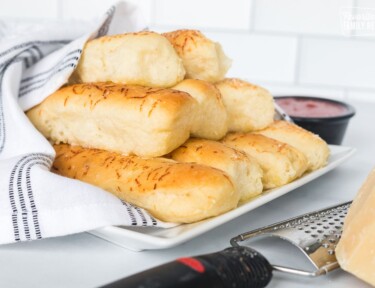 Soft and fluffy breadsticks bundled together and wrapped in a kitchen towel