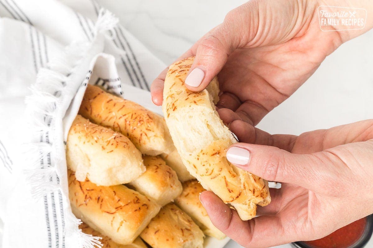 A breadstick being pulled apart to show light and fluffy texture inside.