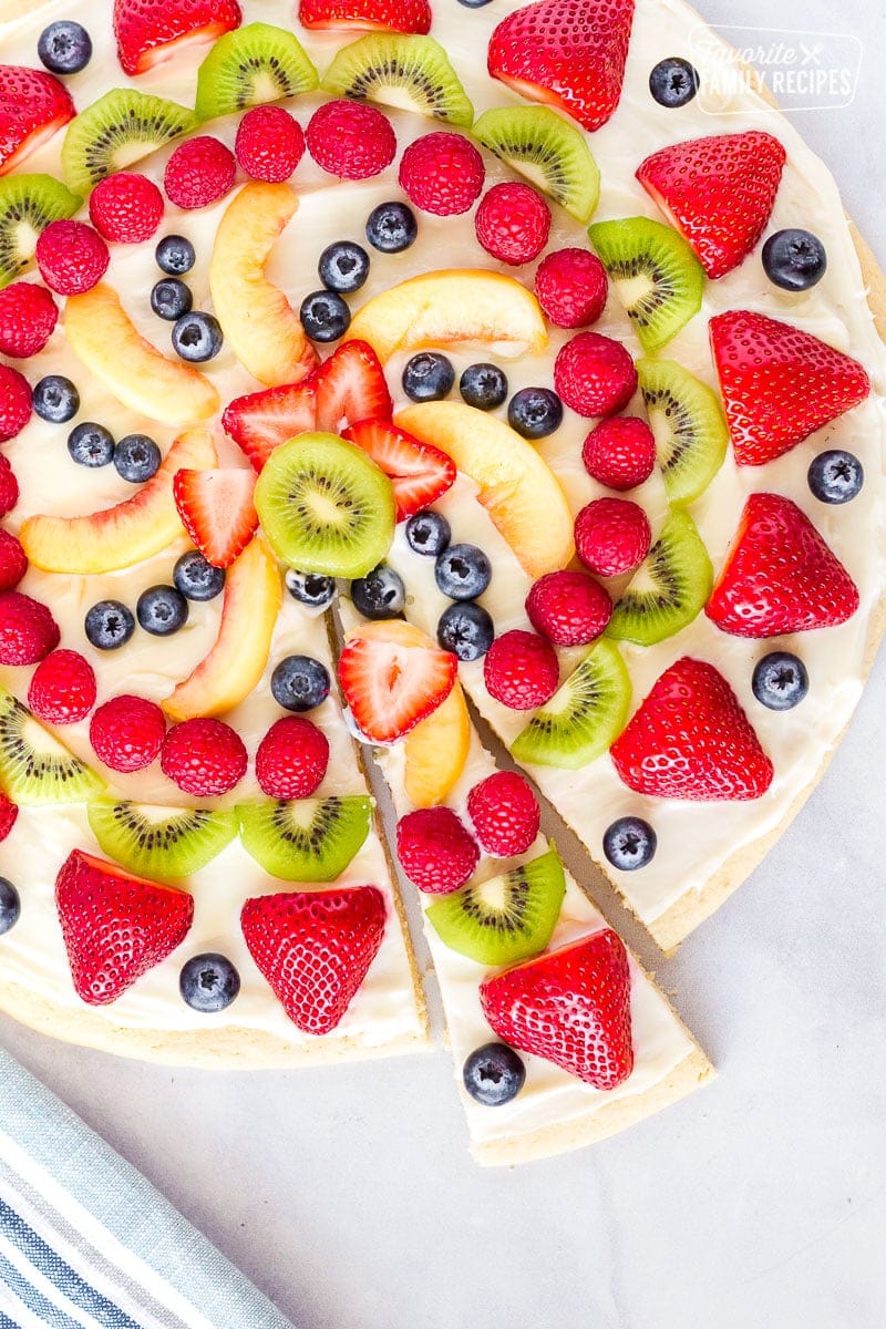 Top view of a whole easy fruit pizza with a slice slightly separated.