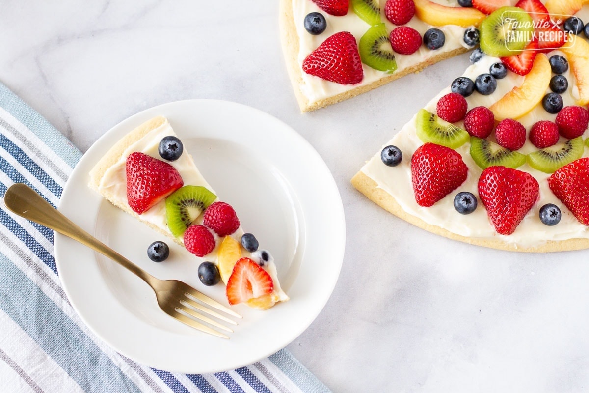 Slice of fruit pizza on a serving plate with fork.
