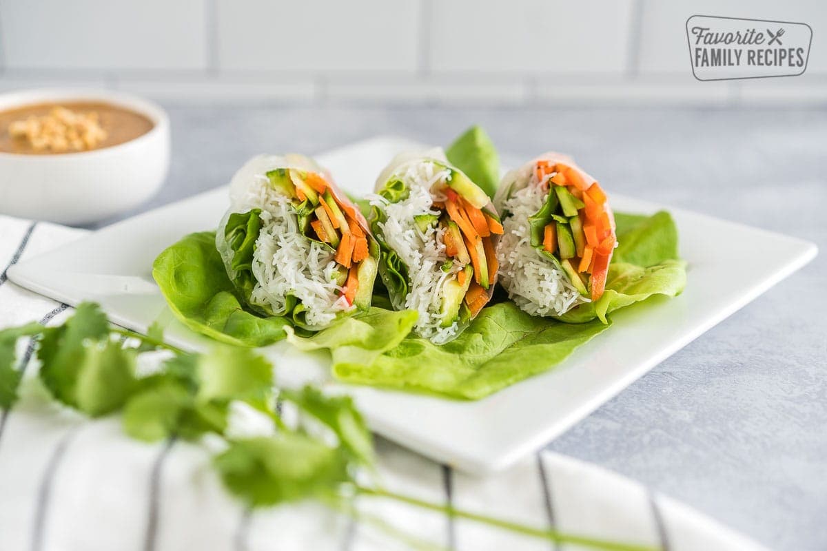 Three fresh spring rolls cut in half on a bed of lettuce.