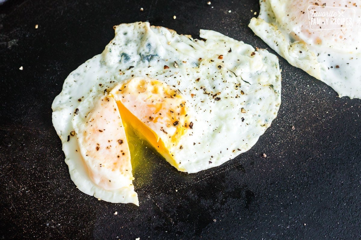 A fried egg on a griddle cooked to over medium