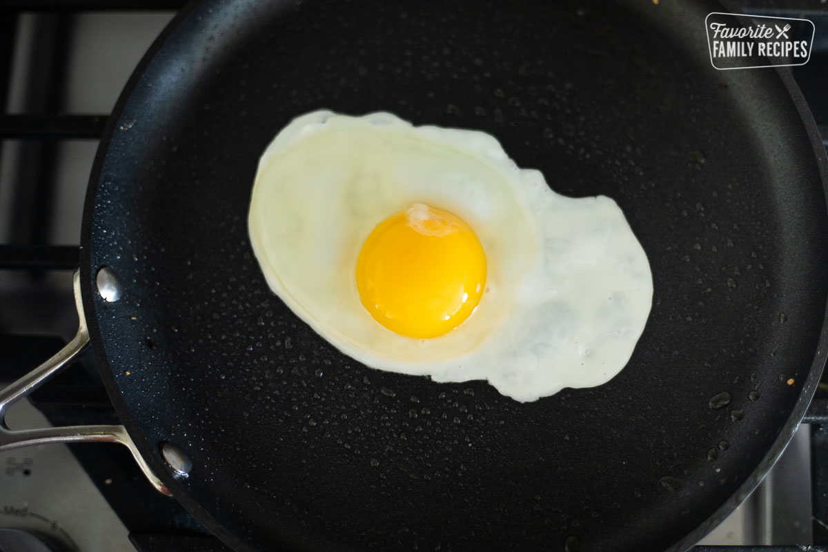 An egg that has been broken into a pan and is being fried