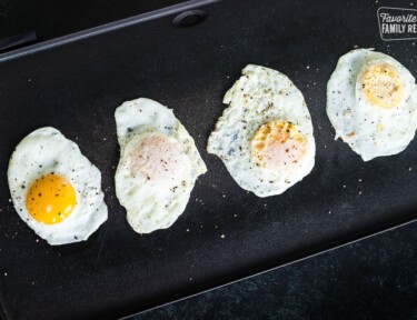 Fried eggs on a griddle cooked 4 different ways: sunny side up, over easy, over medium, and over hard