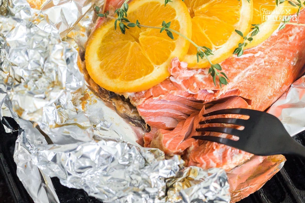 A fork pulling apart a piece of grilled salmon.