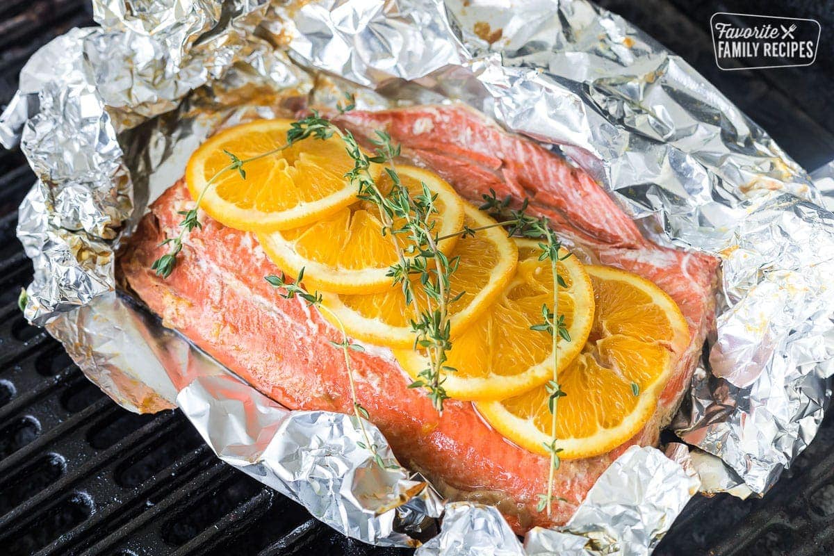 A foil packet with salmon and orange slices over the top