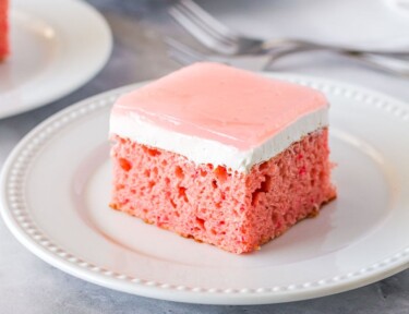 Square slice of Hawaiian guava cake on a plate with two additional plates of cake.