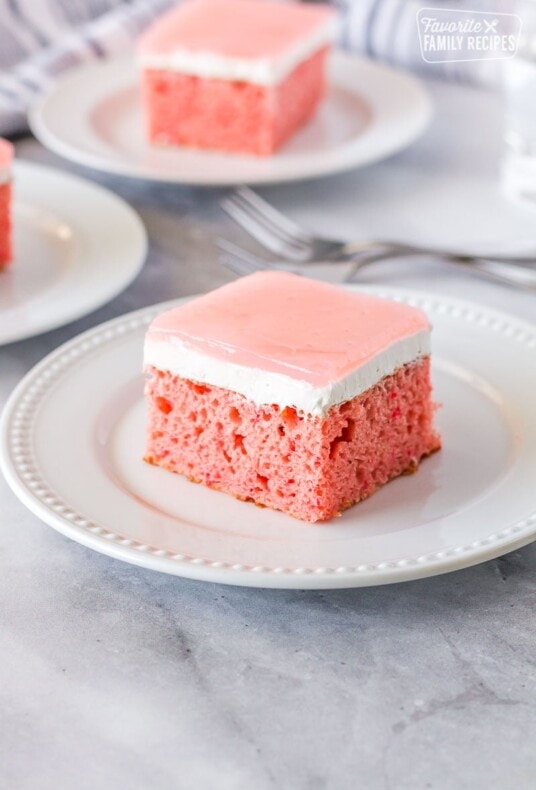 Square slice of Hawaiian guava cake on a plate with two additional plates of cake.