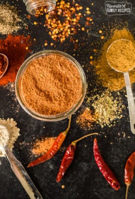 Taco seasoning in a jar with chilies and other ingredients on the table around it