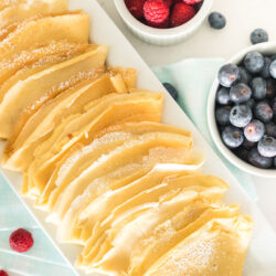 Plain homemade crepes on a white serving platter
