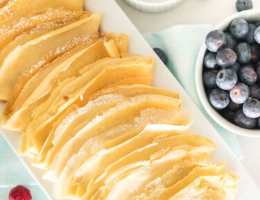 Plain homemade crepes on a white serving platter