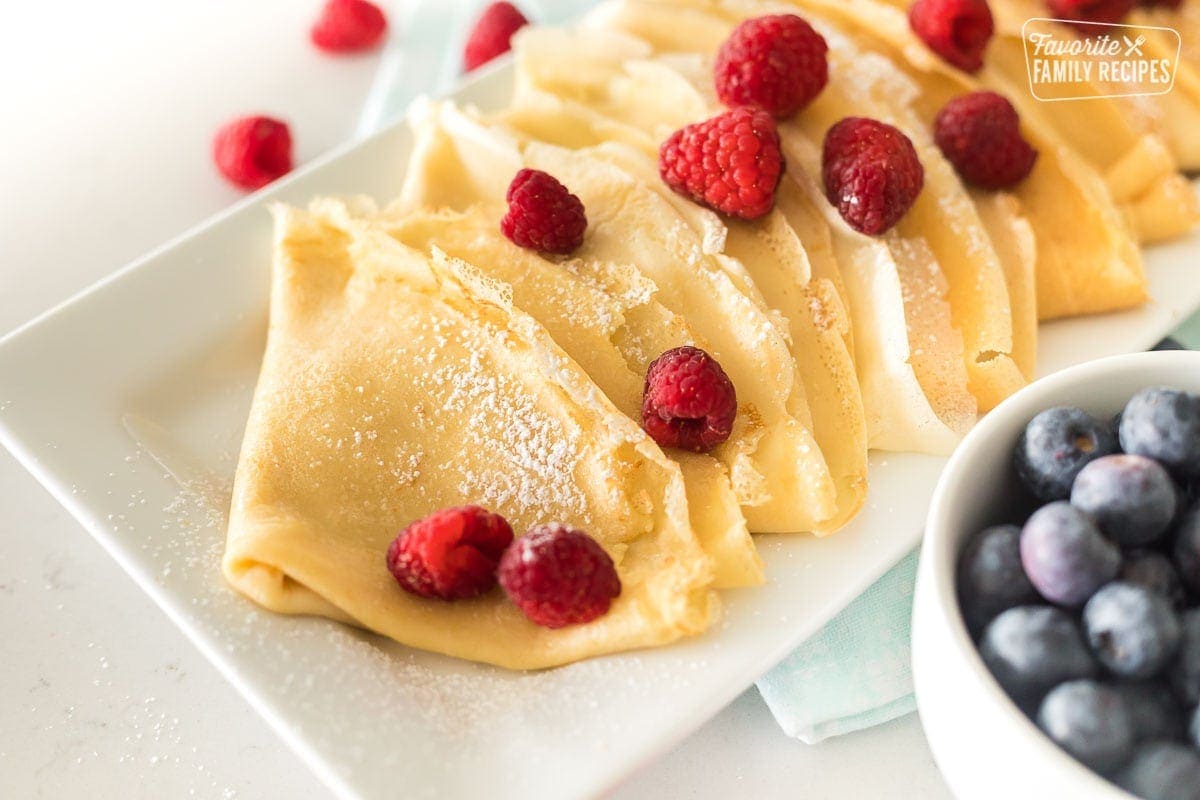 A close up of layered, folded crepes on a white plate. Zoomed in to show texture of thin crepes.