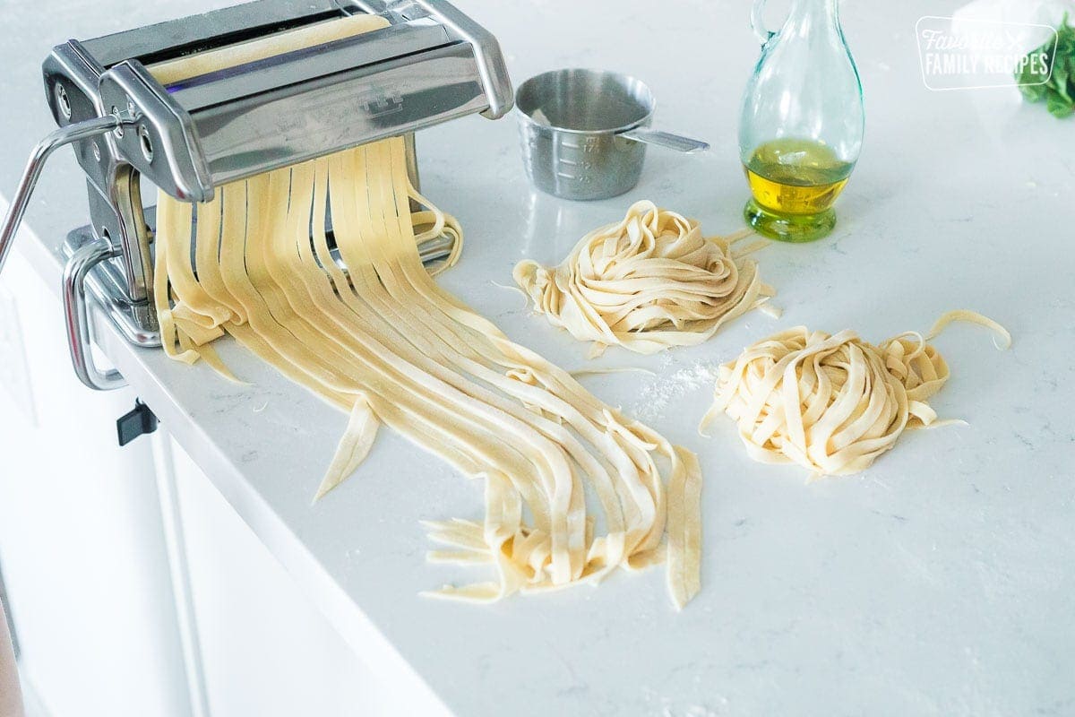 A pasta maker machine on a countertop with homemade pasta noodles