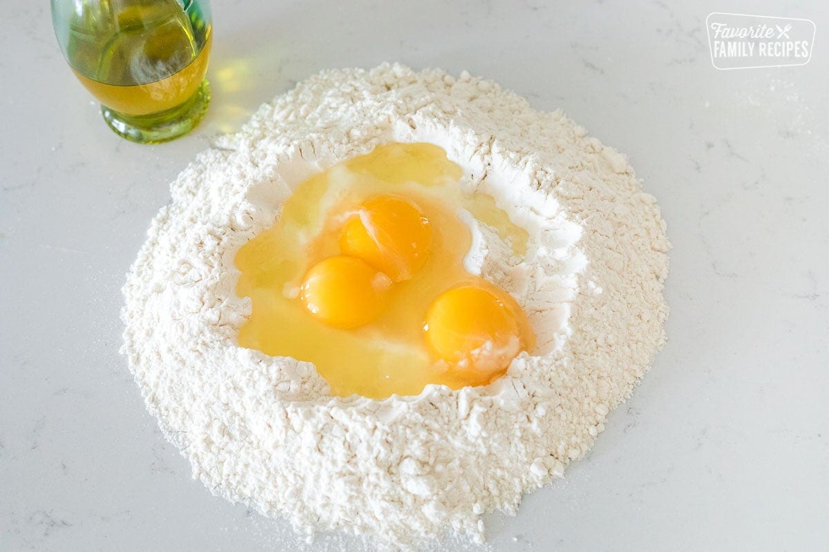 Three eggs inside a well of flour on a cooking surface