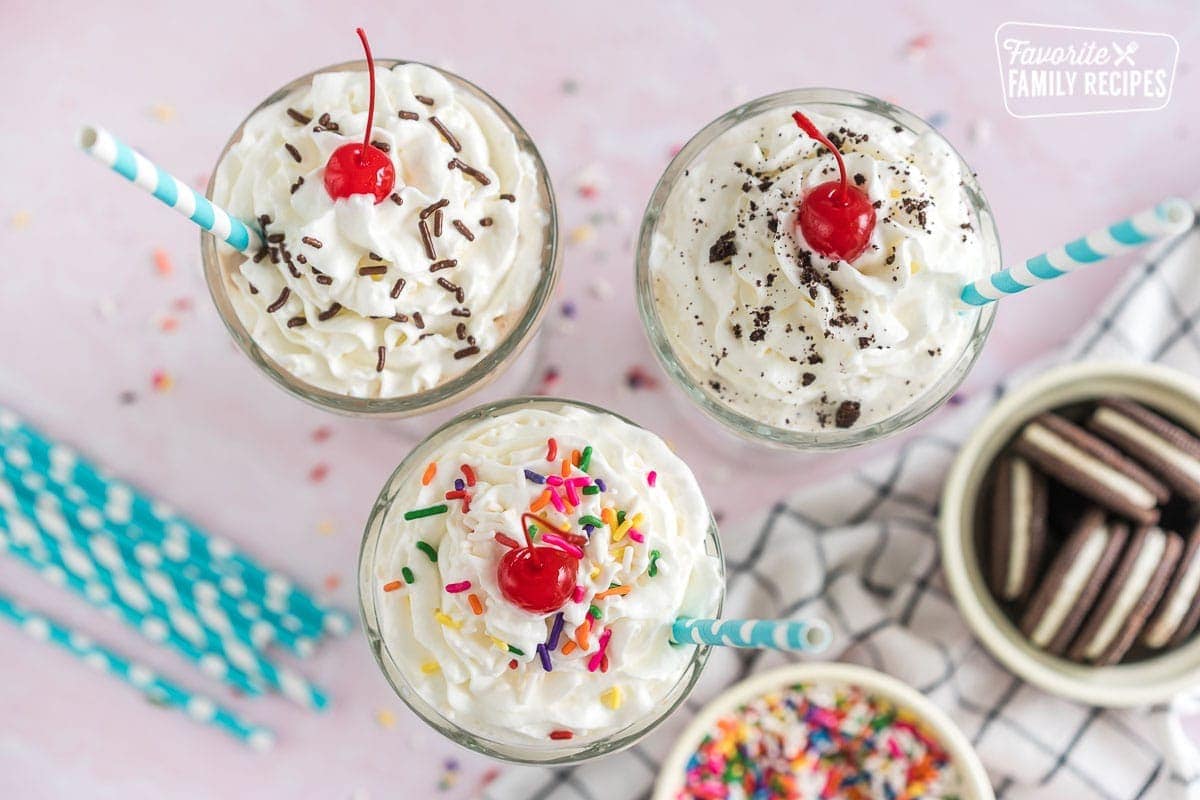 How to Make a Milkshake - three milkshakes topped with whipped cream, sprinkles, and maraschino cherries