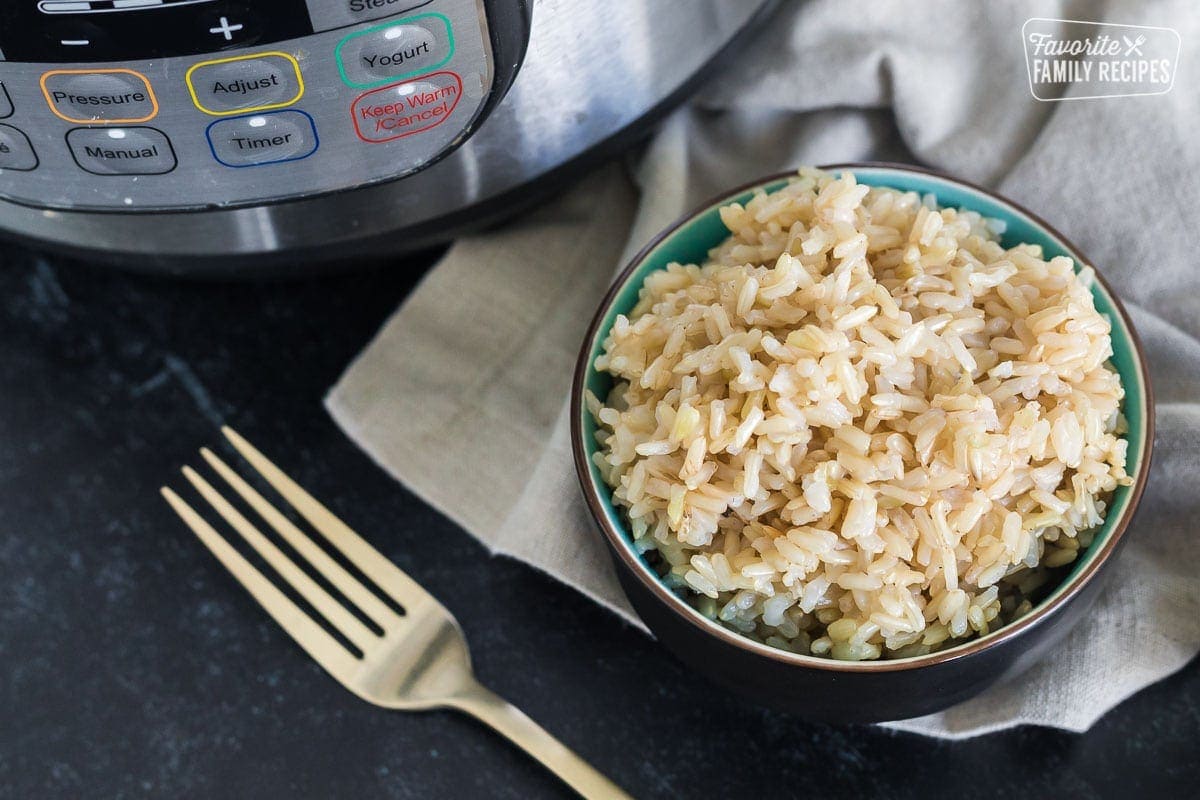 Cooked brown rice in a small bowl next to an Instant Pot.