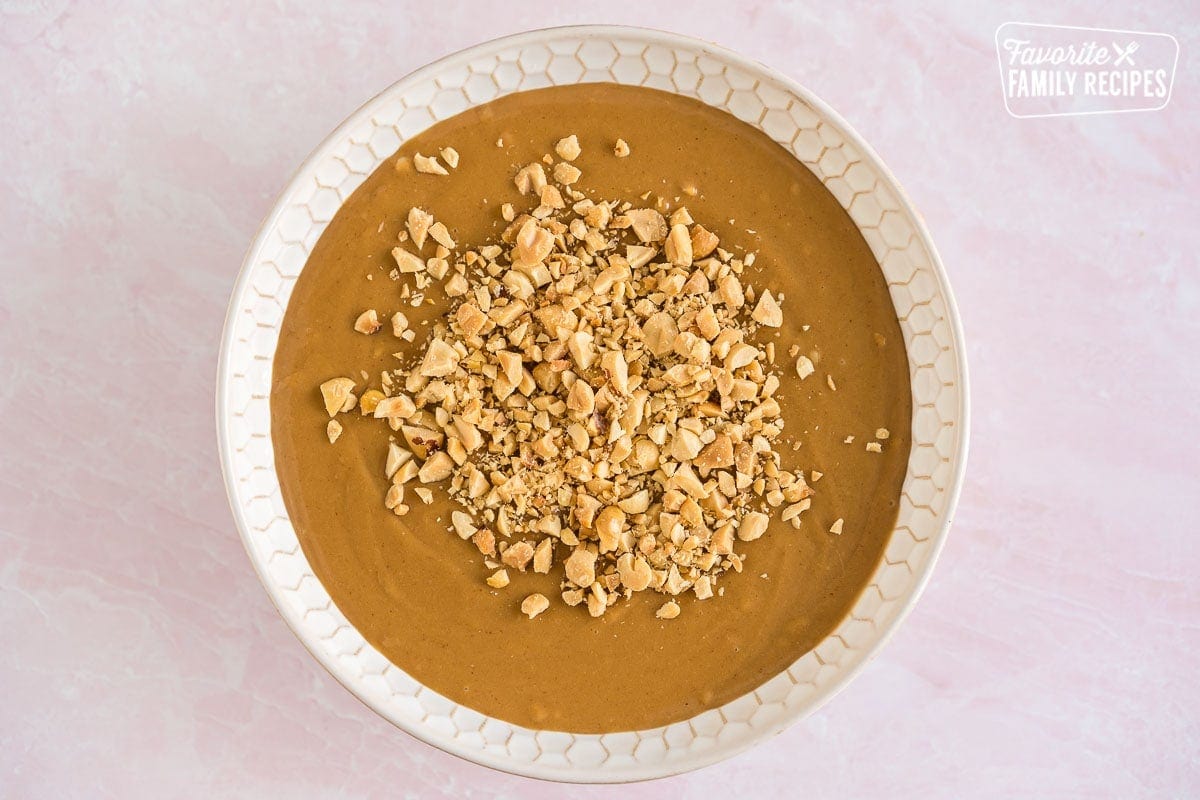 A bowl of peanut sauce topped with chopped peanuts
