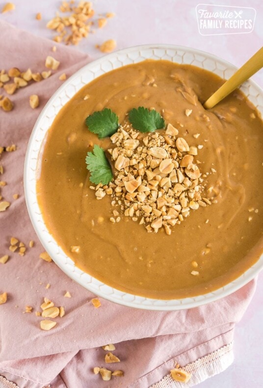 A bowl of peanut sauce topped with chopped peanuts and cilantro leaves