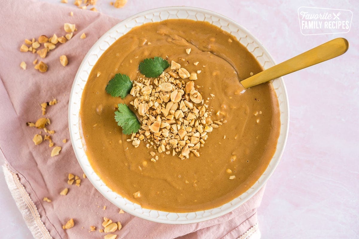 A bowl of peanut sauce topped with chopped peanuts and cilantro leaves