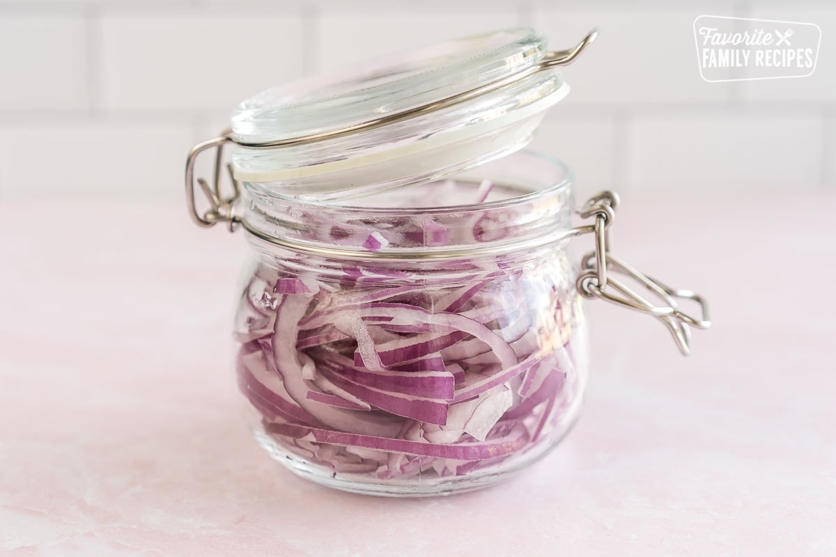 Thinly sliced red onions in a jar with a lid