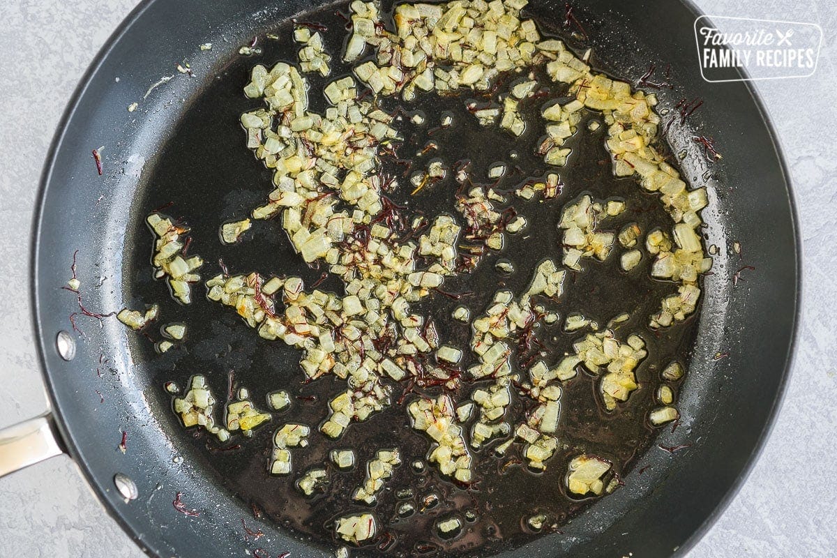 Onions, garlic, and saffron cooked in oil in a large black pan