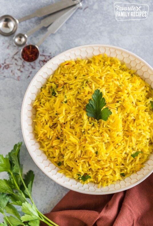 A large bowl of saffron rice topped with a parsley leaf