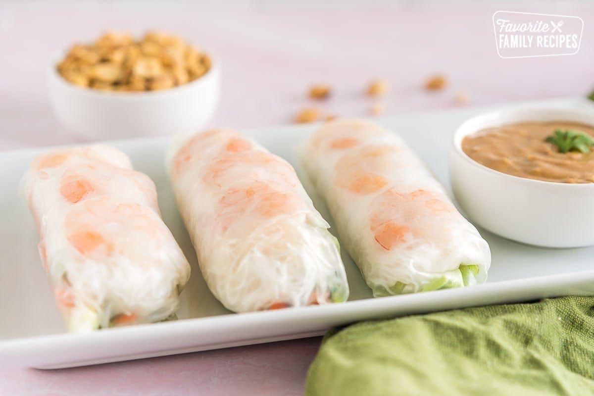 Three Shrimp Spring Rolls on a plate with a bowl of peanut dipping sauce