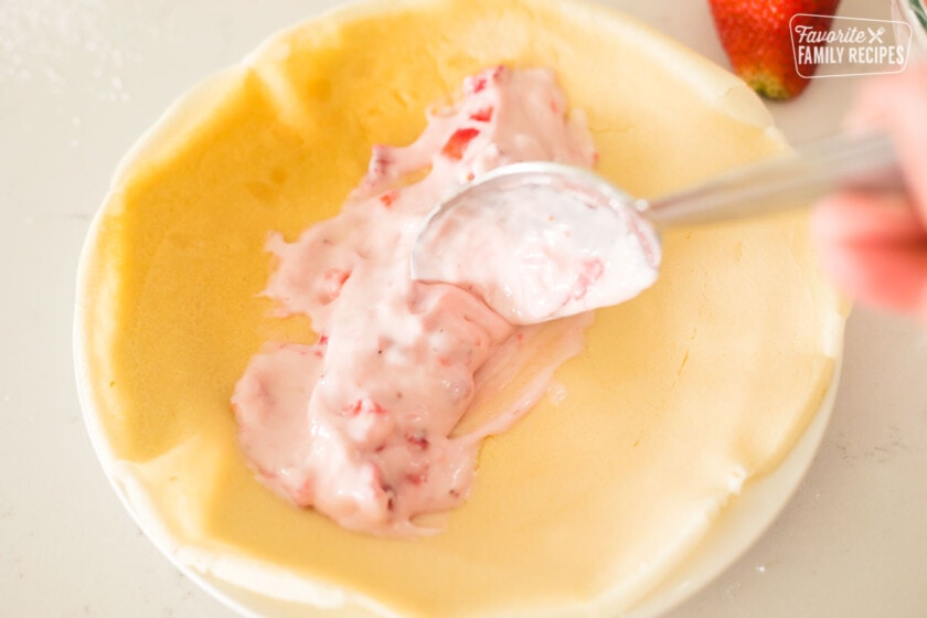 Strawberry cream cheese filling being spread onto a thin crepe