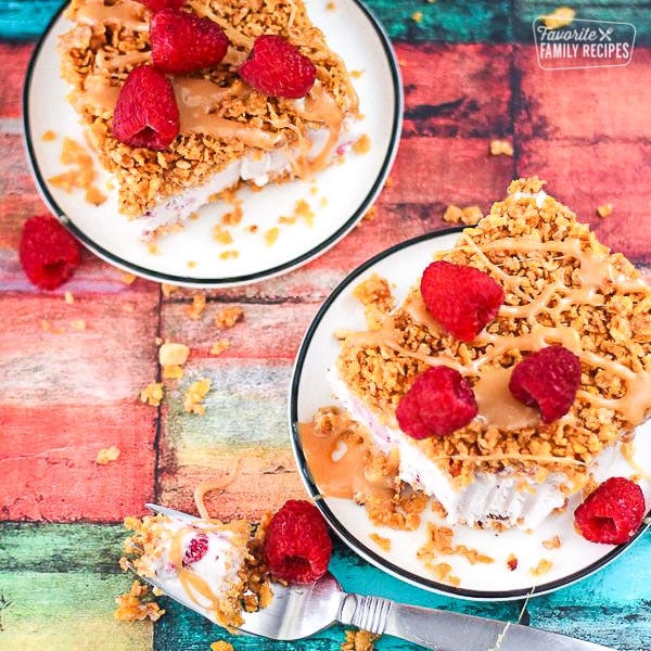 Two slices of raspberry fried ice cream on plates topped with fresh raspberries.