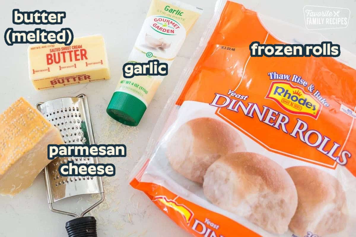 These light and fluffy garlic breadsticks couldn't be easier! They are made with frozen rolls, then rolled in butter and garlic and sprinkled with cheese before baking. A bag of frozen rolls, garlic paste, a stick of butter, and parmesan cheese on a table top