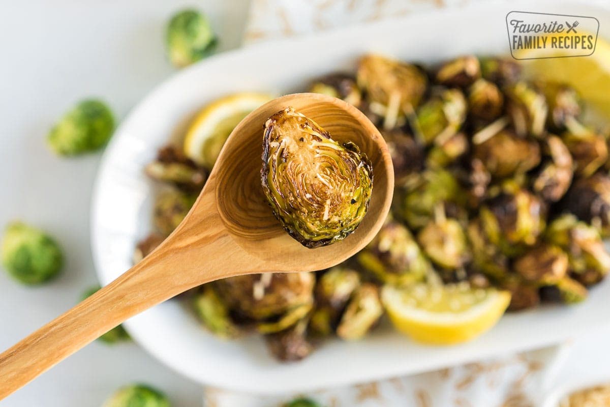 A half Brussels sprout on a wooden spoon after being cooked in an air fryer
