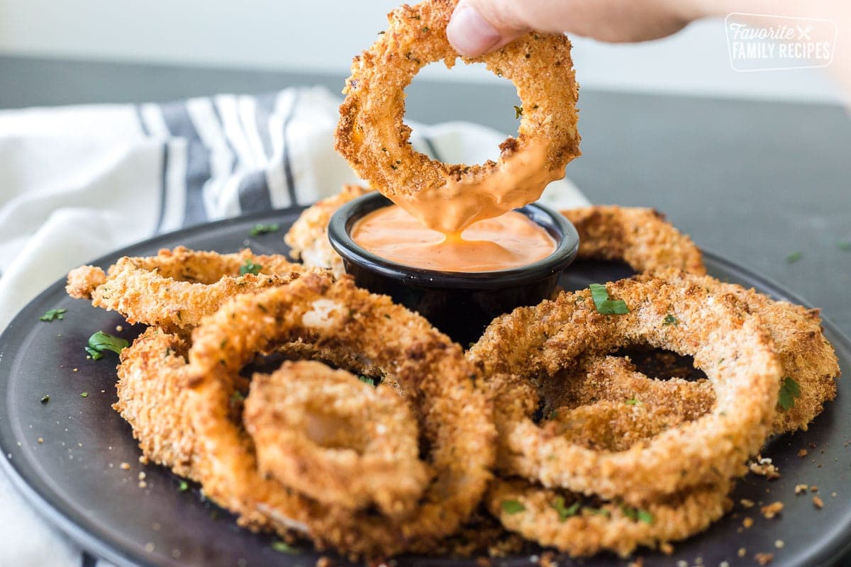 An onion ring made in the air fryer being dipped in sauce