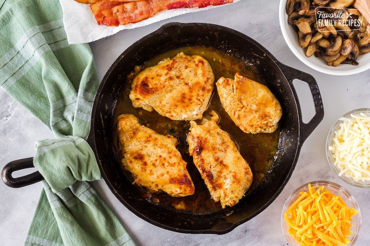 Seared chicken breasts in a cast iron skillet to make Alice Springs Chicken.