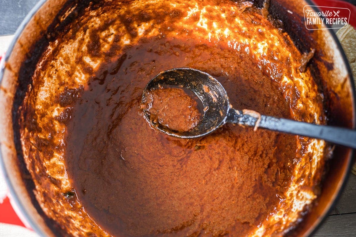 Sauce made from birria in a Dutch oven with a ladle