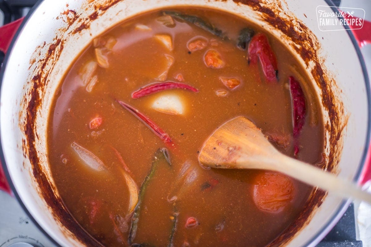 Peppers, onions, chiles, tomatoes, seasonings, and broth in a large Dutch oven to make sauce for birria