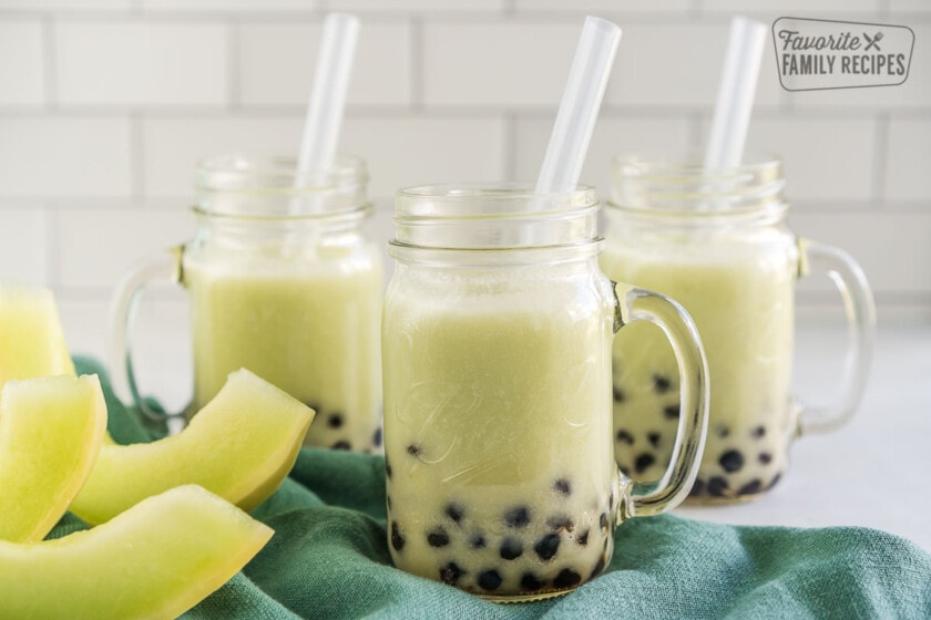 Three honeydew boba smoothies in mason jar mugs with boba straws