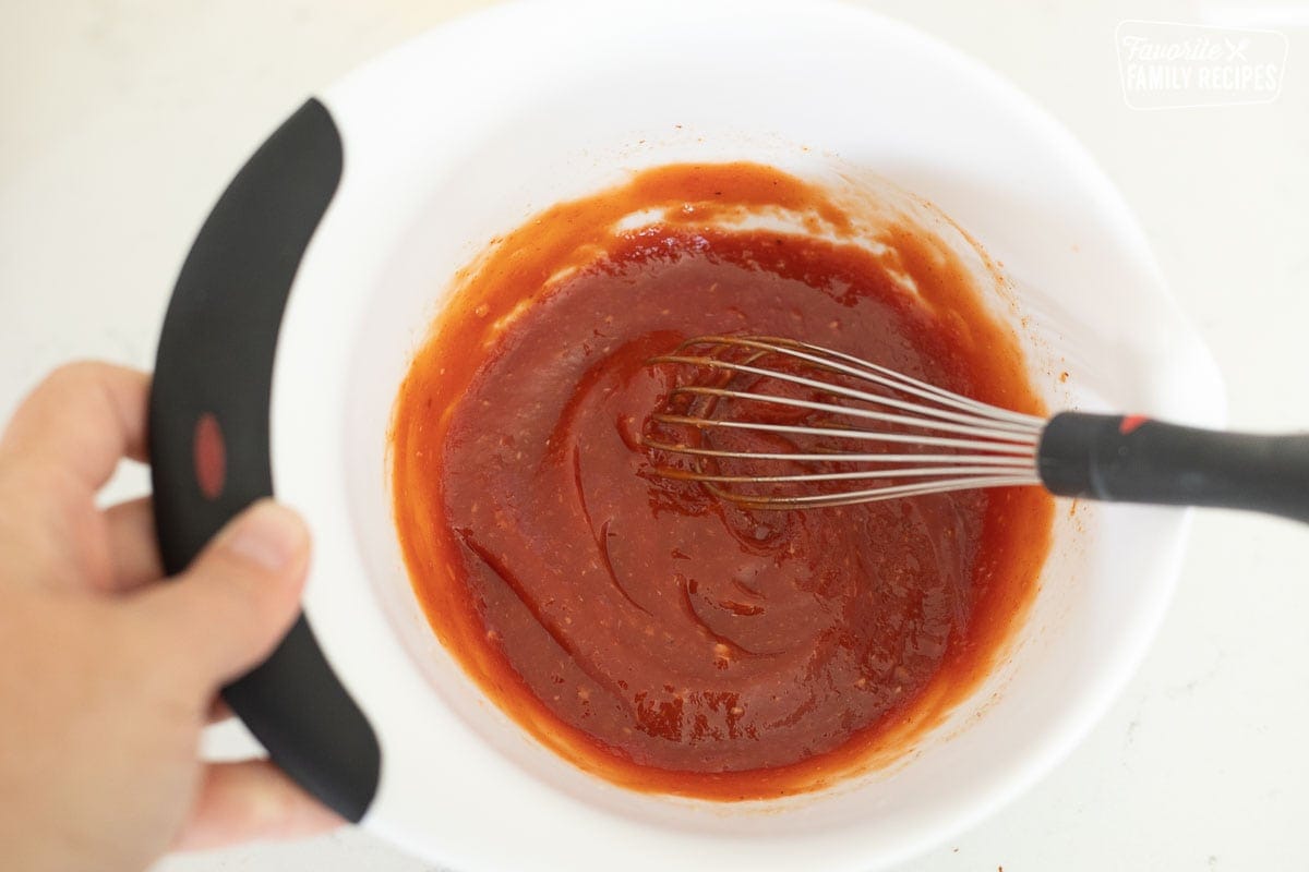 A small mixing bowl of cocktail sauce with a whisk