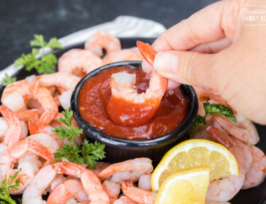 A shrimp being dipped into cocktail sauce