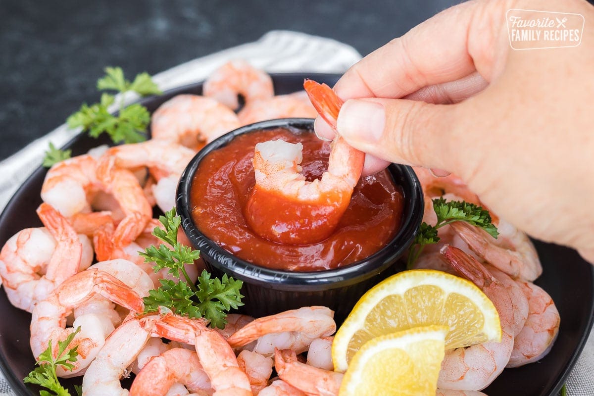 A shrimp being dipped into cocktail sauce