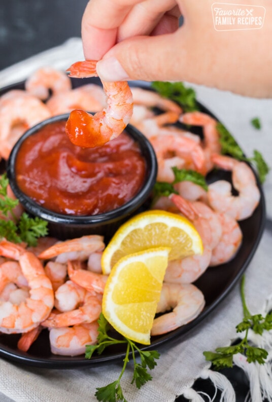A shrimp being dipped into homemade cocktail sauce