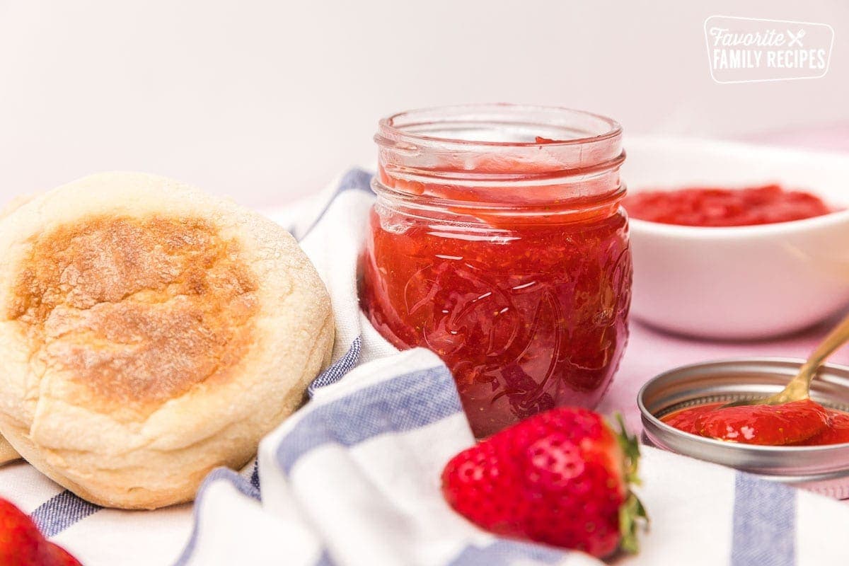 Processed strawberries in bowl and jar with english muffins