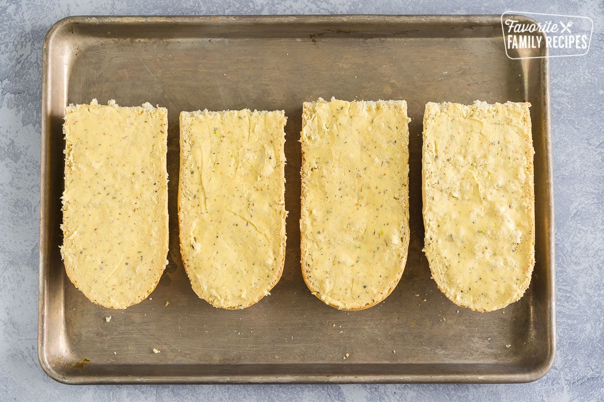 Four halves of french bread coated with garlic butter.