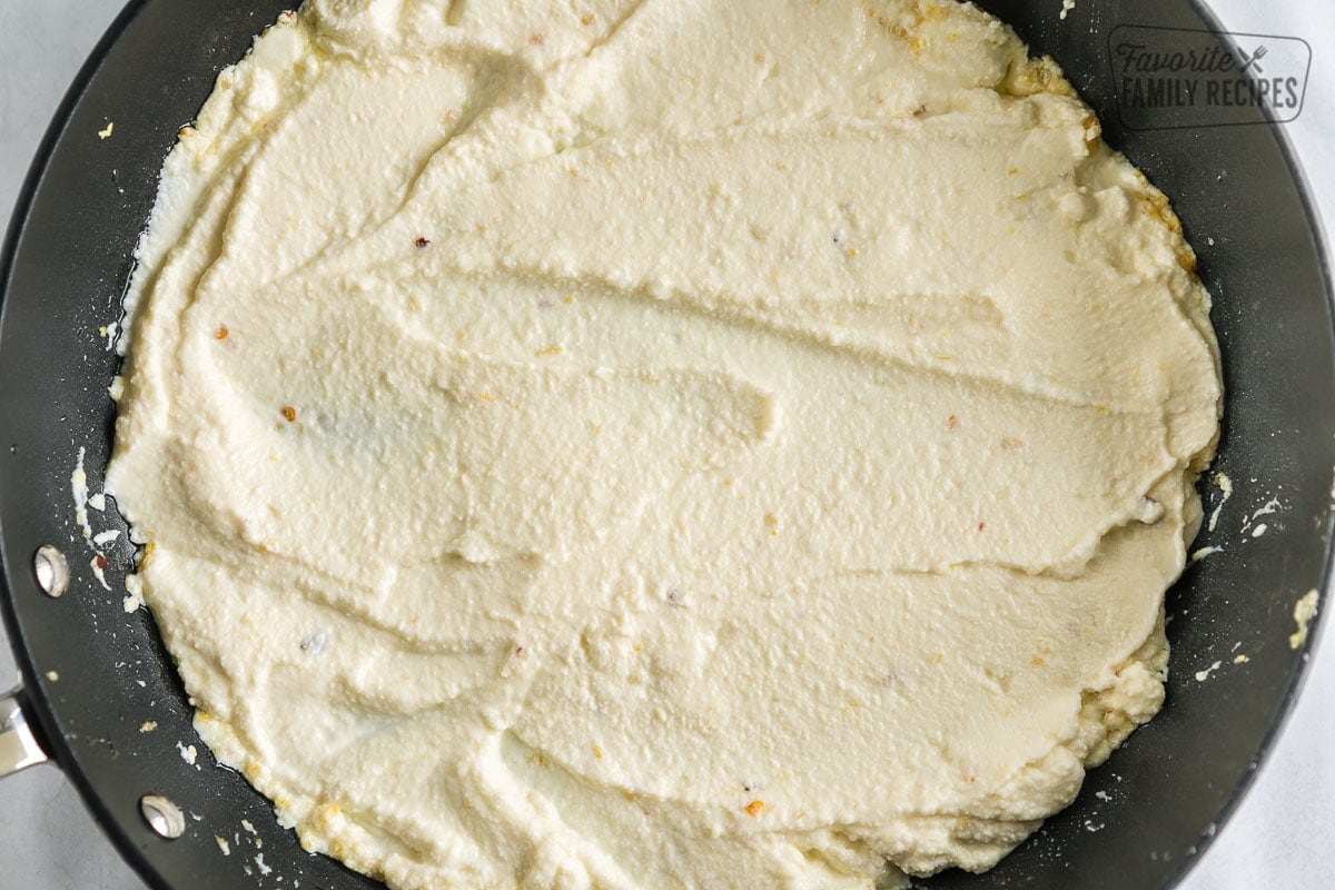 Ricotta cheese in a pan mixed with spices and oil