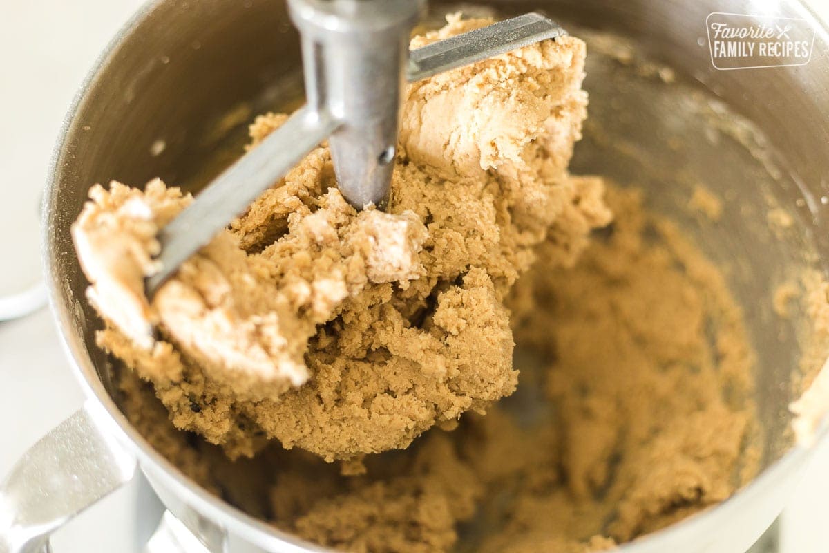 A mixing bowl with a paddle attachment mixing cookie dough