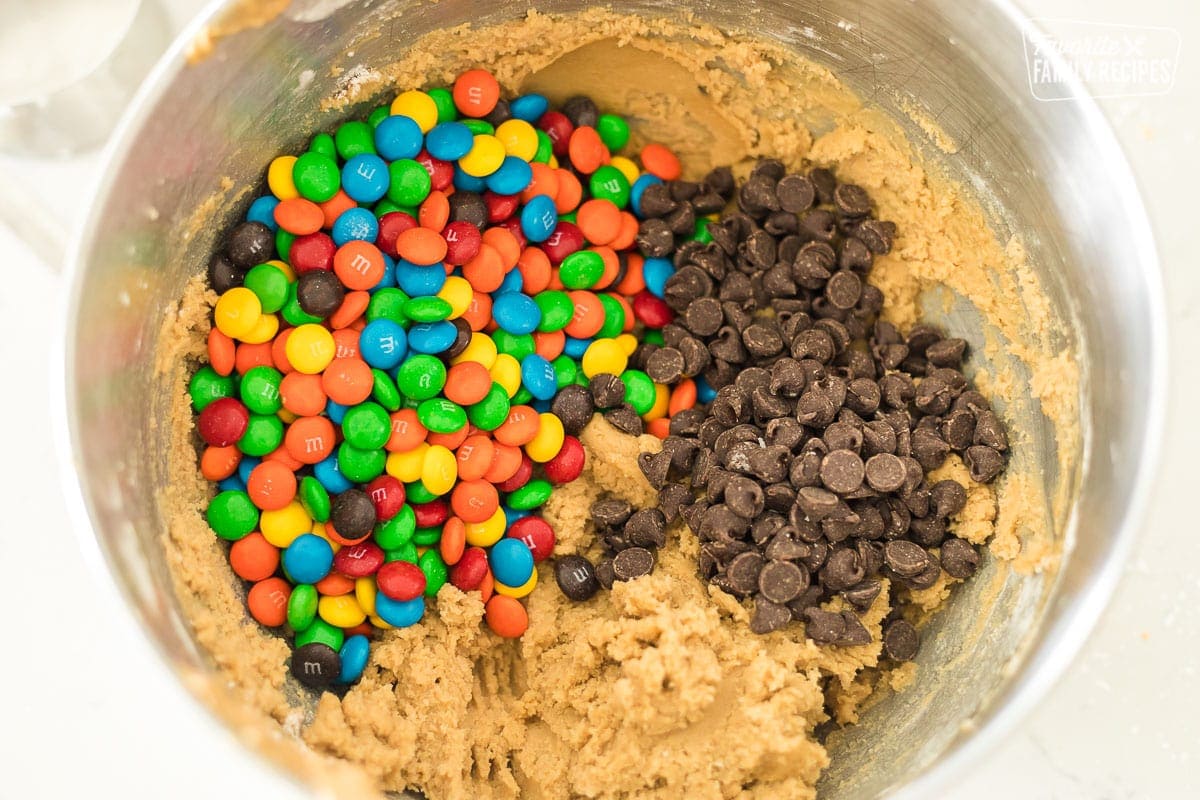 Cookie dough with a pile of M&M and chocolate chips over the top