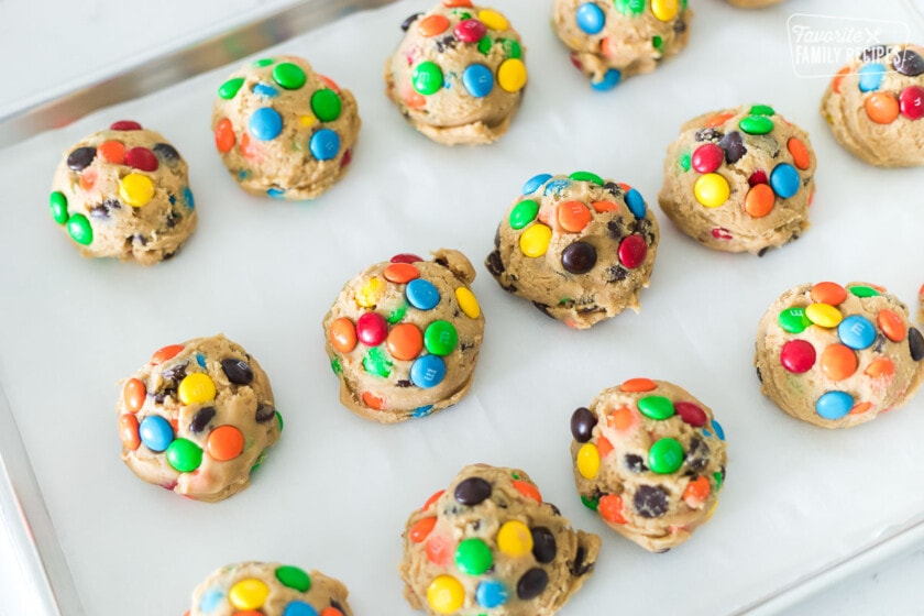 M&M cookie dough balls that have been refrigerated and placed on a cookie sheet
