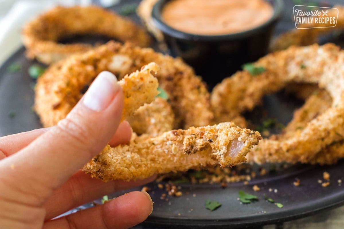 Close up of an onion ring with a bite out of it to show crispiness